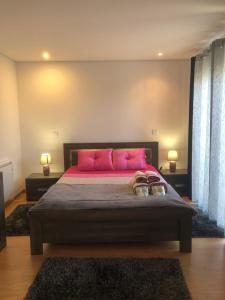 a bedroom with a large bed with pink pillows at Casa do Palheiro in Pitões das Júnias +2 photos