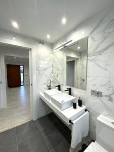 a white bathroom with a sink and a mirror at Apartamentos el Oligo in Cadavedo