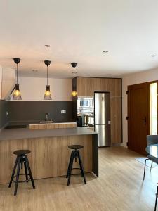 a kitchen with a counter and two stools in it at Apartamentos el Oligo in Cadavedo