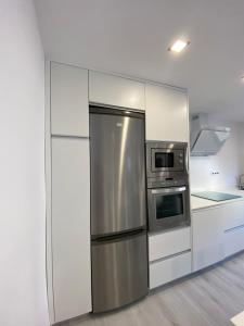 a kitchen with white cabinets and a stainless steel refrigerator at Apartamentos el Oligo in Cadavedo