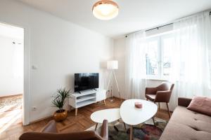 - un salon avec un canapé, une télévision et une table dans l'établissement OMA's Apartment in Haus GRETE, à Bad Waltersdorf