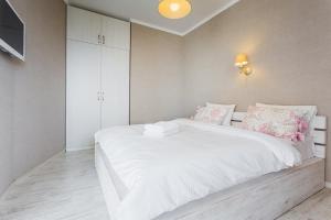 1 dormitorio con 1 cama blanca grande con almohadas rosas en Панорамный вид 15 этаж. Набережная Днепра, en Kiev