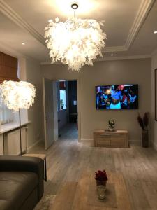 a living room with two chandeliers and a tv on the wall at Luxury apartment in Old Town in Klaipėda