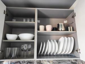 a cupboard filled with white plates and utensils at Premium apartman Family in Paralia Katerinis