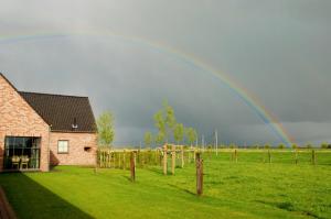 a rainbow in the sky over a field with a house at Vakantiehuis NIEUWHOF in Gistel +6 photos