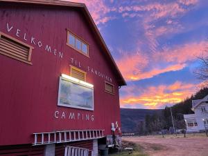 a red barn with the sunset in the background at Sandviken Camping in Austbygdi