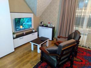 a living room with a tv and a chair and a table at Dom Semya Gusar in Qusar