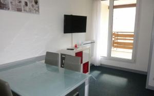 a room with a glass table with a television on it at Appartement au pied des pistes in Les Deux Alpes