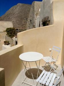 a table and chairs sitting next to a mountain at Castelli Loggia in Emporio Santorini