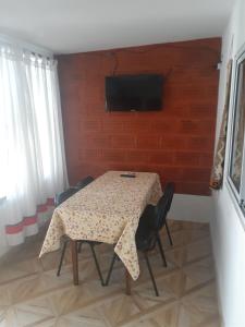 mesa con sillas y TV en la pared en Hostal Candelaria en Cafayate
