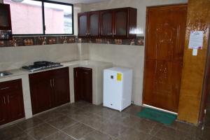 uma cozinha com armários de madeira e um frigorífico branco em Hostal Flor de los Ángeles em Guamote