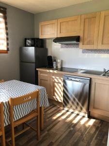 uma cozinha com uma mesa, um frigorífico e uma máquina de lavar louça em Cottage 4 personnes dans domaine privé em Signy-le-Petit