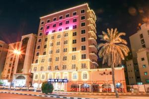 a large building with a pink light on it at Ruwi Hotel Apartments, Sharjah in Sharjah