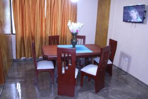 - une table à manger avec des chaises et un vase fleuri dans l'établissement Hostal Flor de los Ángeles, à Guamote