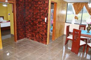Habitación con pared de ladrillo, mesa y sillas. en Hostal Flor de los Ángeles en Guamote