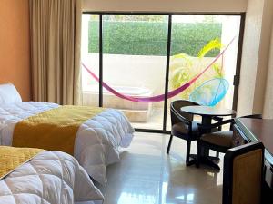a hotel room with two beds and a table and chairs at Hotel Los Aluxes in Mérida