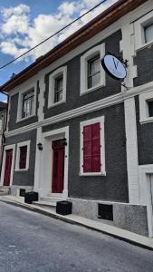 een zwart-wit gebouw met rode deuren en een klok bij Variante Hotel in Konak