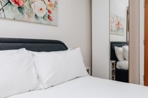 a bedroom with a white bed and a mirror at Central Modern Flat for 4-6 & dedicated parking in Henley on Thames