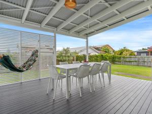 a white dining table and chairs on a deck at Rosena - The Classic Beach House - 5 Cashmore Street in Evans Head