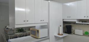 een keuken met witte kasten en een magnetron bij Annwin Annex in Saint James