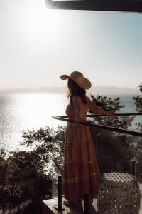 una mujer con un sombrero de pie en un balcón con vistas al océano en Naatooh Guest Houses en Florianópolis