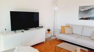een woonkamer met een witte bank en een flatscreen-tv bij Veronique Apartment in Nazaré