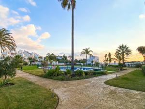 park z palmą i basenem w obiekcie Golf Gardens Miraflores - Bright and spacious apartment w mieście Mijas Costa