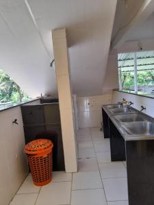 a large kitchen with two sinks and a trash can at Pousada Milton in Angra dos Reis