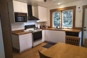 La cuisine est équipée de placards blancs et d'un four avec plaques de cuisson. dans l'établissement Moon Dance Cabin, à Madeira Park