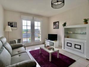 a living room with a couch and a tv at Normandy Confort - WIFI & CALM - Bayeux Centre in Bayeux
