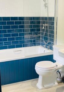 The Wilcove Inn في توربوينت: حمام من البلاط الأزرق مع مرحاض وحوض استحمام