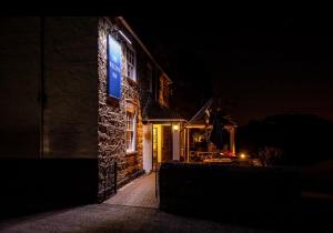 a building with a blue sign on the side of it at night at The Wilcove Inn in Torpoint