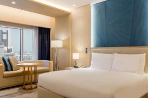 Habitación de hotel con cama y silla en The Diplomat Radisson Blu Hotel Residence & Spa, en Manama