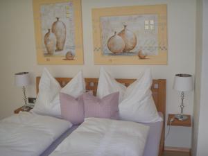 ノイシュティフト・イム・シュトゥーバイタールにあるLandhaus Knoflachのベッド1台(白い枕付)、壁に2枚の絵が飾られています。