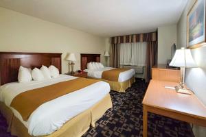 a hotel room with two beds and a desk at Comfort Inn & Suites in Shakopee