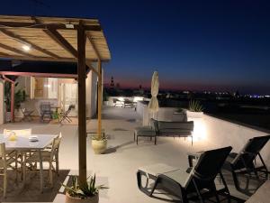 a patio with tables and chairs on a roof at night at dallalbaltramonto in Lecce