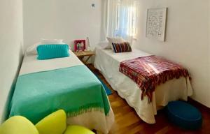 a bedroom with two beds and a chair in it at Casa das Cores in Sesimbra