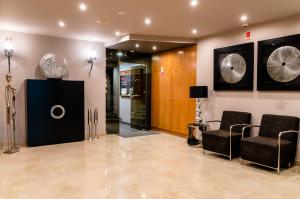 a room with two chairs and a wall with clocks at Hotel Bocage in Setúbal