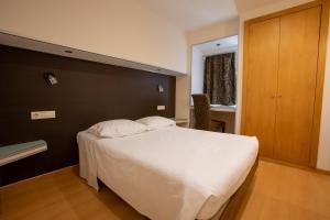 um quarto com uma cama branca e uma parede de madeira em Guesthouse Bocage em Setúbal