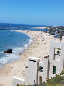 a beach with a white building and people on it at CLOUD NINE - Comfort & Elegance in Irvine
