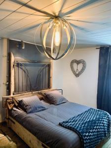 1 dormitorio con 1 cama grande y lámpara de araña en Ferme d'Audelange, en Audelange
