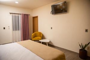 - une chambre avec un lit, une chaise et une télévision murale dans l'établissement Hotel Casa Jima Agave, à Tequila
