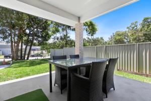 a glass table and chairs on a patio at Bribie Getaway Villa in Bongaree