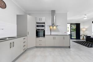 a white kitchen with white cabinets and appliances at Bribie Getaway Villa in Bongaree