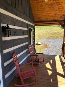 Whitetop的住宿－Cozy Cabin Near Grayson Highlands State Park，两个红色椅子坐在小屋的门廊上