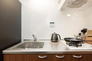 een keuken met een wastafel en een koekenpan op een fornuis bij Ideal Fukushima in Osaka +57 foto's