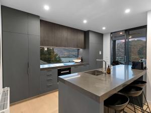 cocina con armarios grises y encimera con fregadero en The Rata Villa, en Queenstown 15 fotos más