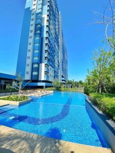 een groot blauw zwembad voor een hoog gebouw bij Lumpini Seaview Cha-am By Siky in Ban Sahakham