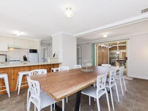 una cucina e una sala da pranzo con tavolo in legno e sedie bianche di Rose Retreat a Port Fairy