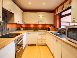 a kitchen with white cabinets and a microwave at Sea-Prize View in Colwyn Bay